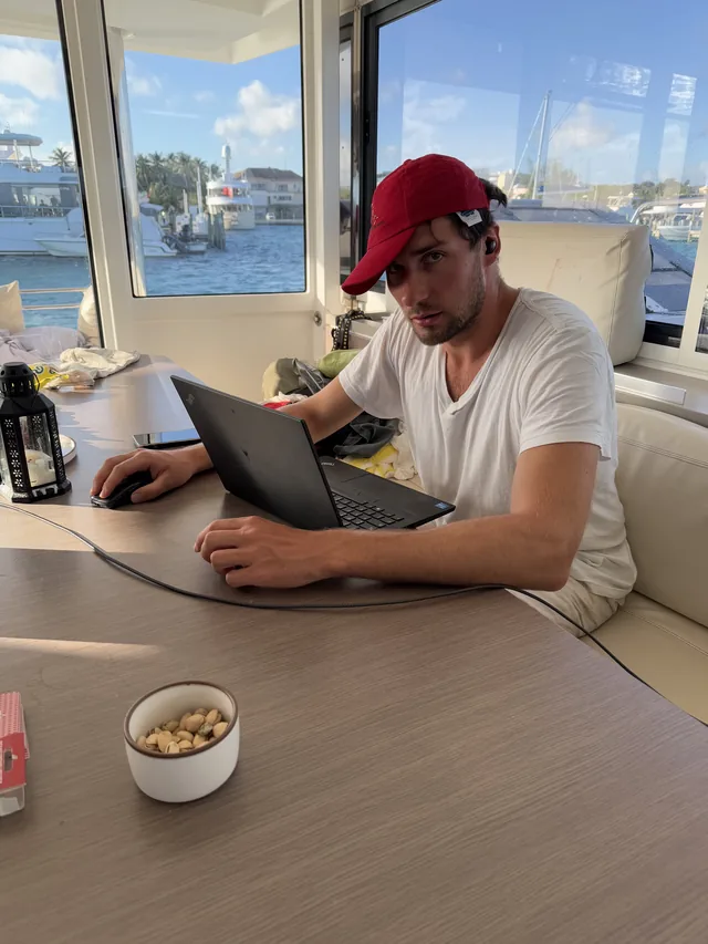 Guido working on a laptop at a table overlooking a marina.